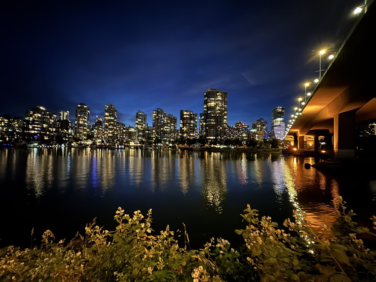 Lit high-rises on False Creek in Vancouver at blue hour, a bridge on the right – companion photo by Bernhard Houy