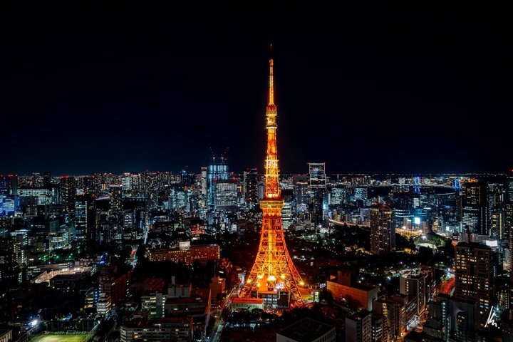Tokyo Tower at night seen from above, with the endless Tokyo skyline and the Rainbow Bridge in the distance – photographic art by Bernhard Houy